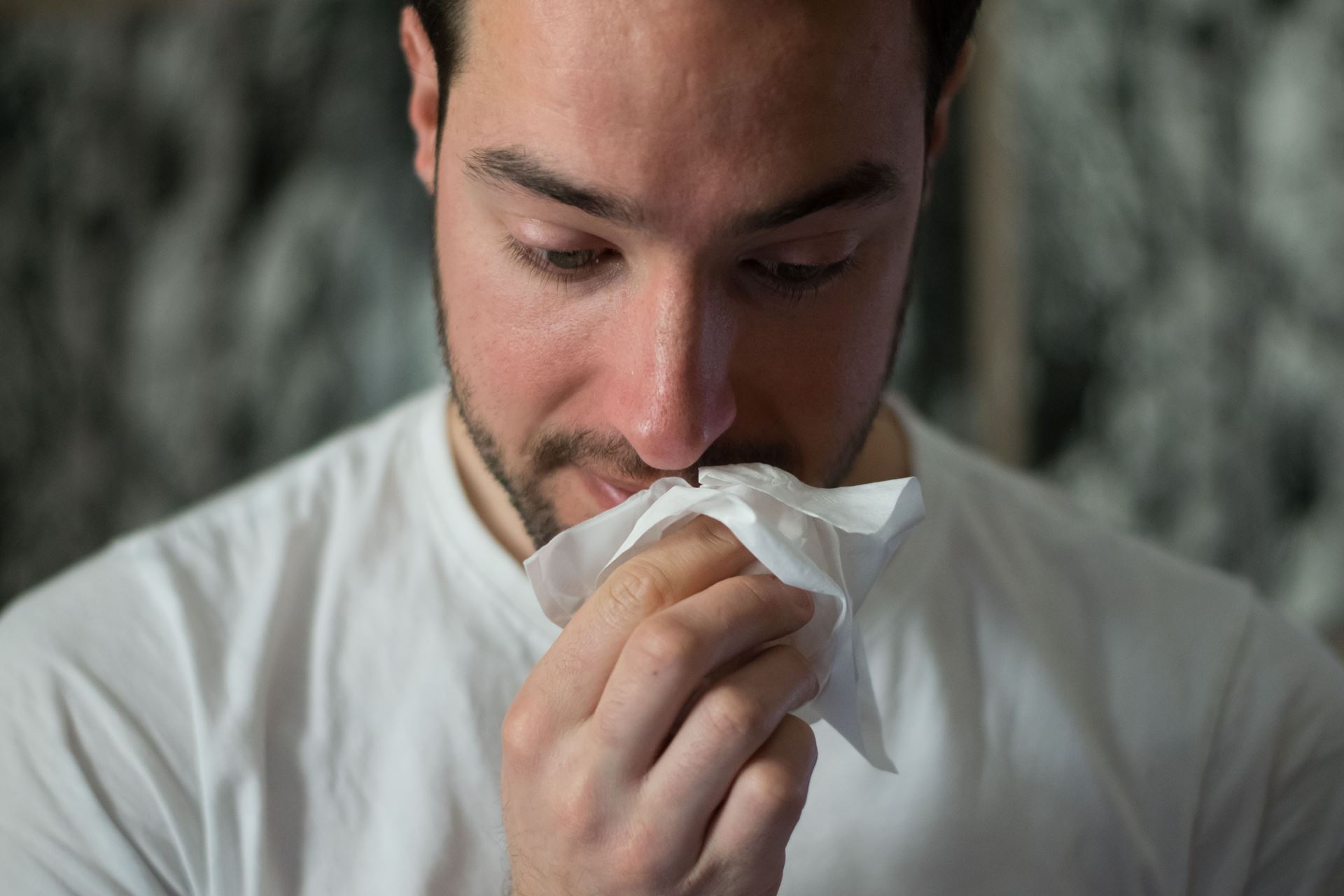 a man with a tissue wiping his nose
