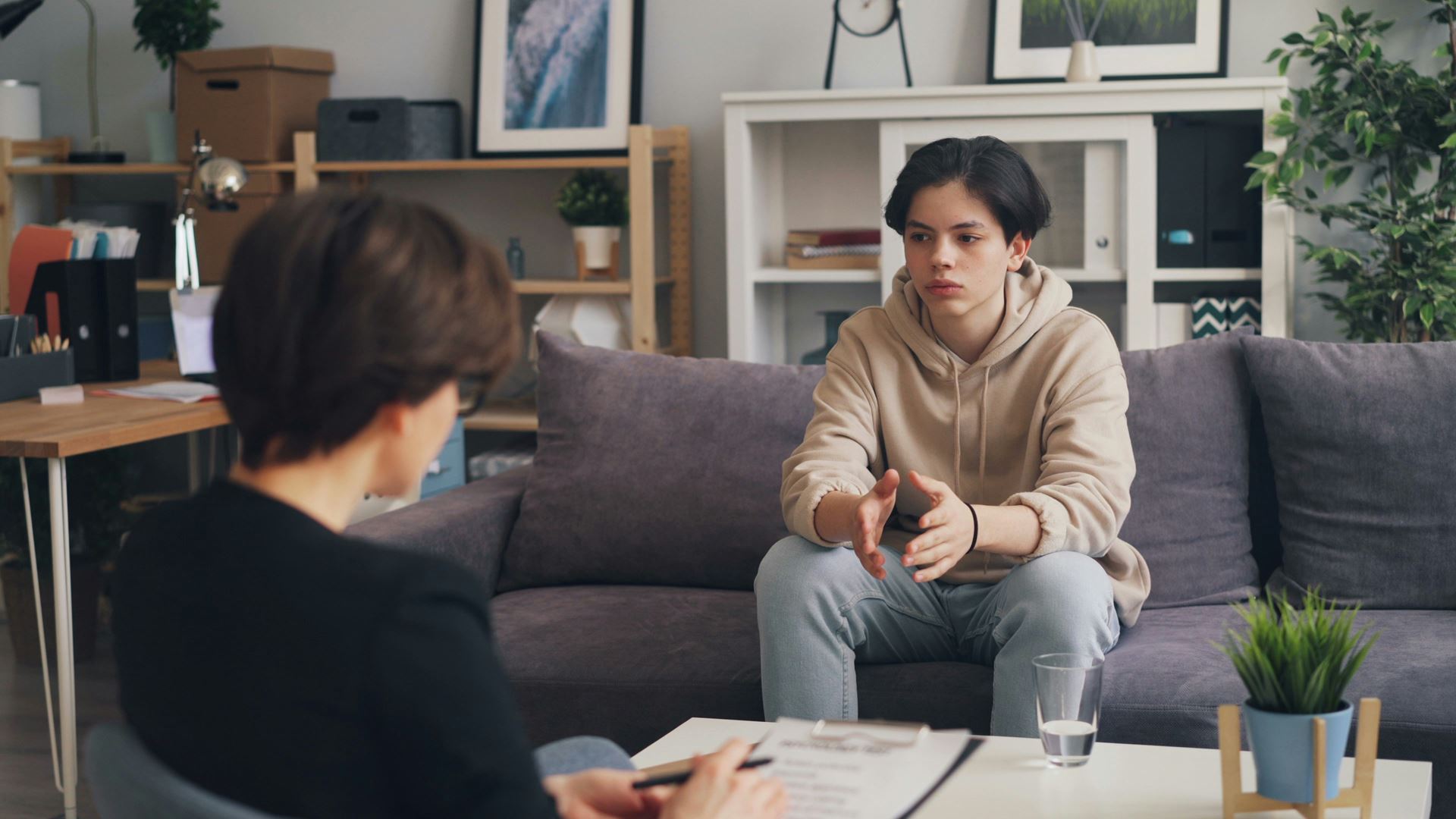 a young male sat on a sofa speaking with an older woman