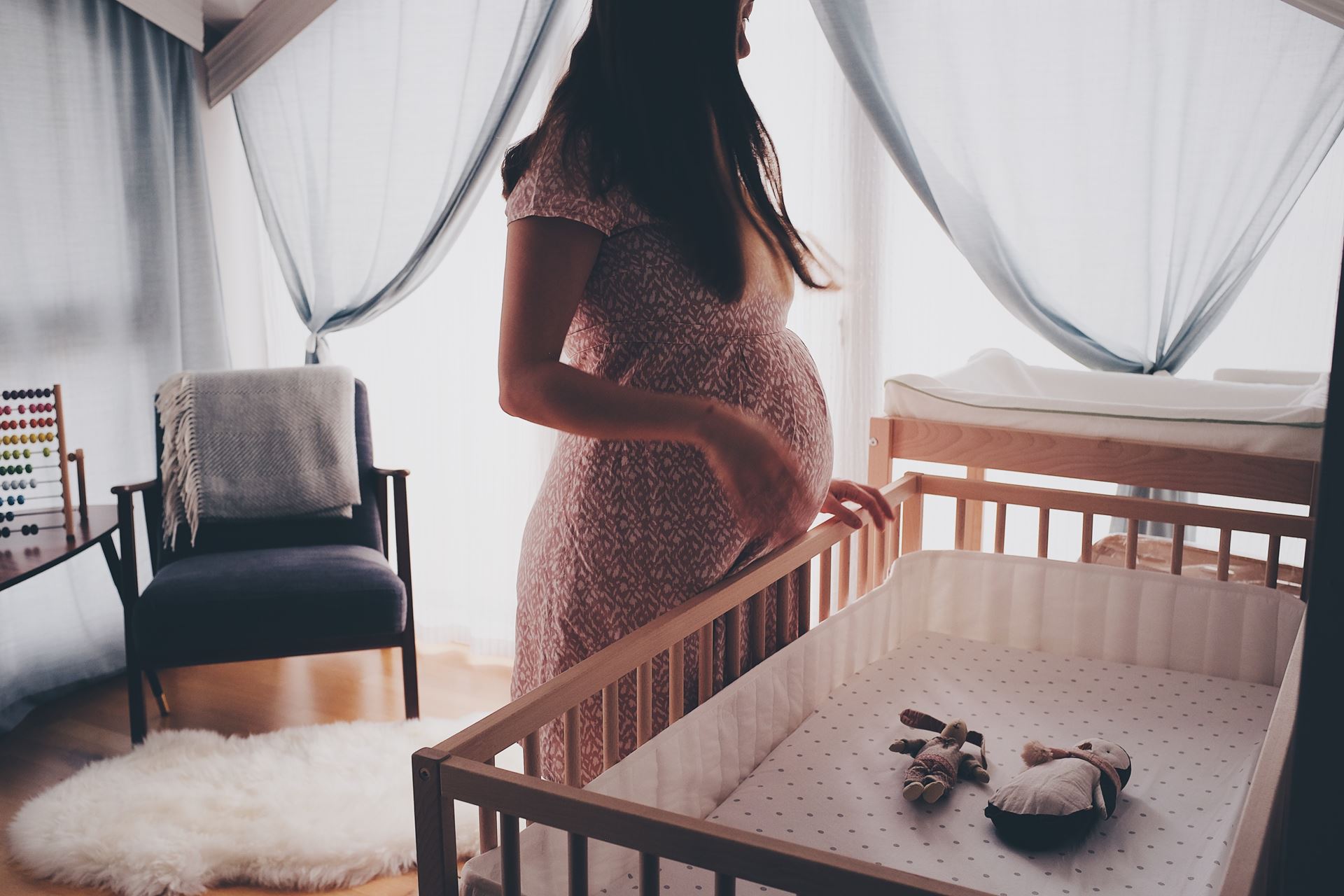 a pregnant woman stood by a crib