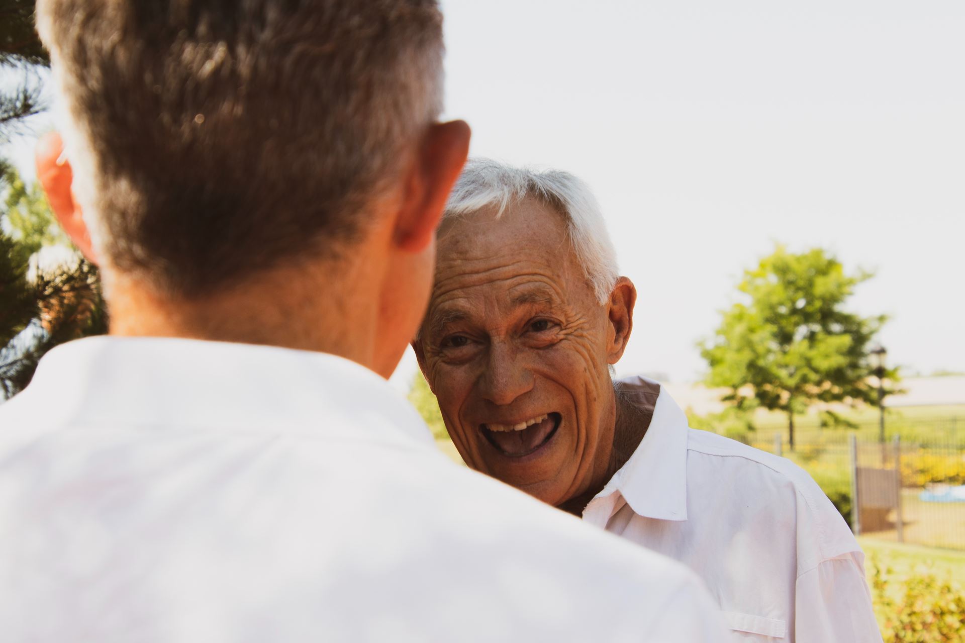 An older man laughing speaking to a younger man