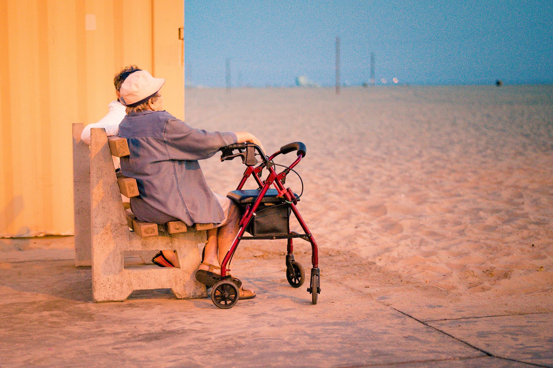 an older person with a rollator sitting overlooking a beach